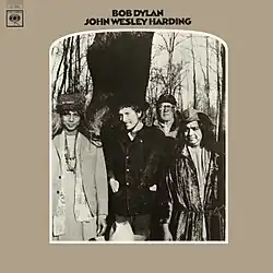 A black-and-white photo of several men standing in a wooded field, with Dylan in the center