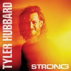 A photo of Hubbard smiling, with an intensely bright orange light glowing behind him and casting a dark red shadow.
