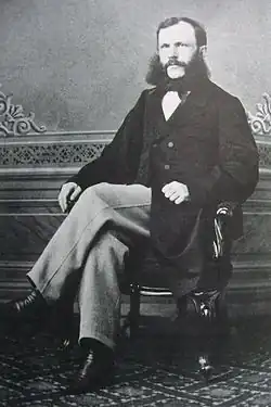 Bomansson with moustache and sideburns sitting cross legged