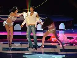 Young man singing, with two young women removing his shirt