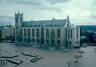 A color photograph of a large university building across a brick square